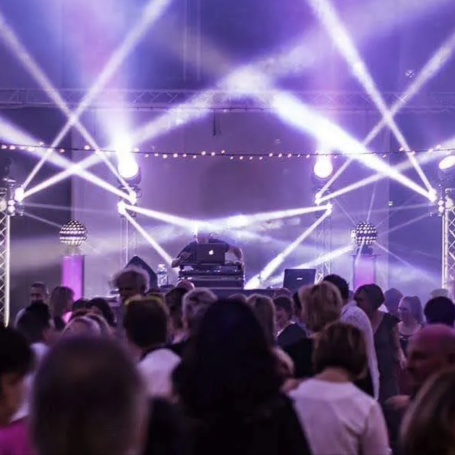 Soirée dansante – Lumières et ambiance festive Foule en train de danser sous des faisceaux lumineux blancs et violets, avec DJ sur scène et ambiance festive lors d’un événement a lyon